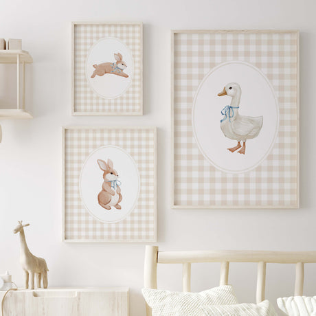Set of three watercolor baby animal nursery prints: bunny with scarf, bunny with bow, goose with bib on a gingham background.
